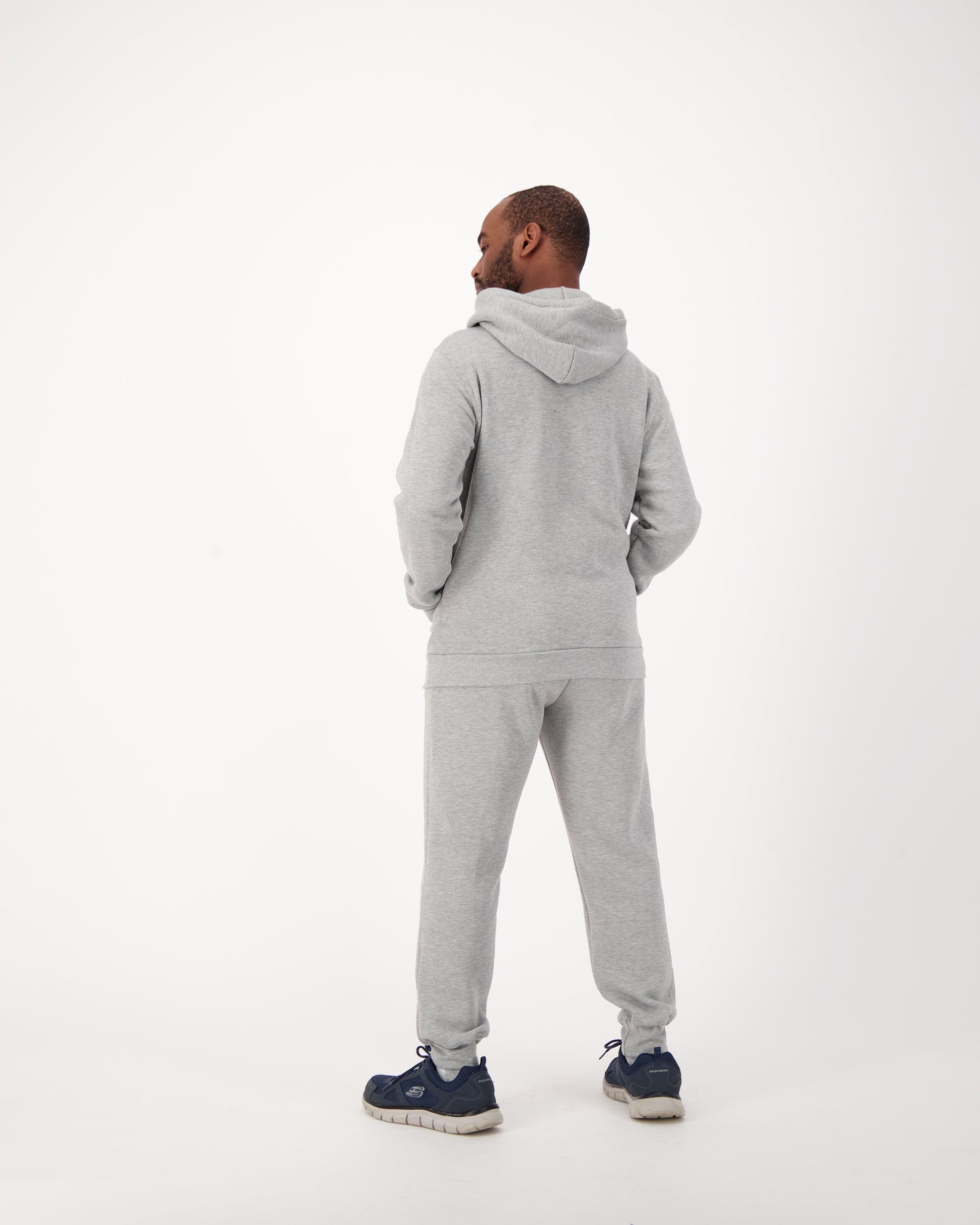 A stylish man wearing a grey sweater and matching sweatpants. He exudes a casual yet refined look. The grey sweater fits him perfectly, providing a sleek silhouette. The sweatpants, also in grey, are relaxed and comfortable. The ensemble creates a modern, fashionable vibe. The man confidently pairs this attire for a trendy and comfortable outfit choice