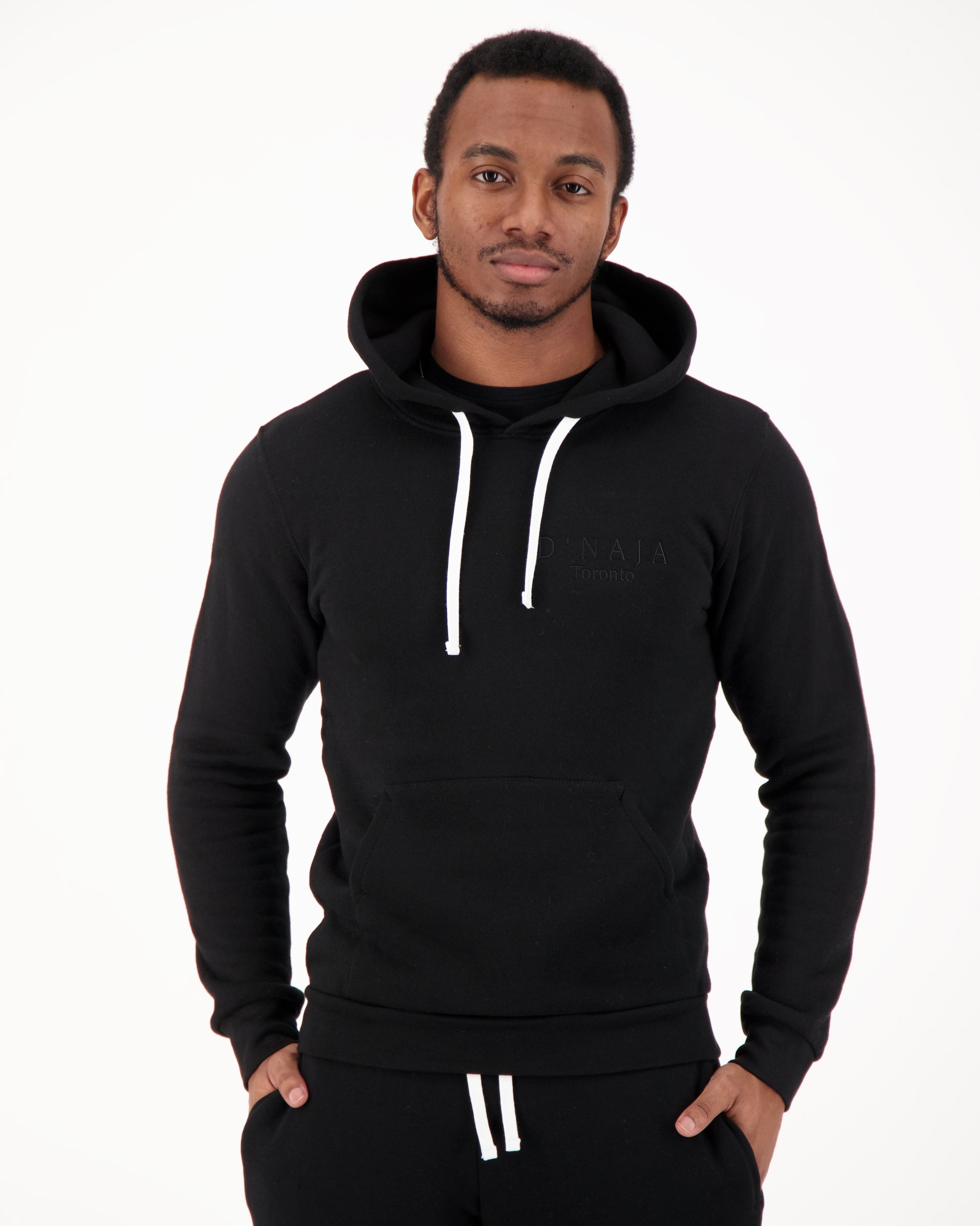 A confident man wearing a black unisex fleece hooded sweatshirt. The sweatshirt is made of soft and cozy fleece fabric, providing warmth and comfort. The black color adds a sleek and timeless aesthetic to the garment. The hooded design offers versatility and extra protection against the elements. The man pairs the sweatshirt effortlessly with his casual attire, exuding a cool and stylish vibe. This black fleece hooded sweatshirt is the perfect choice for both comfort and fashion-forward looks