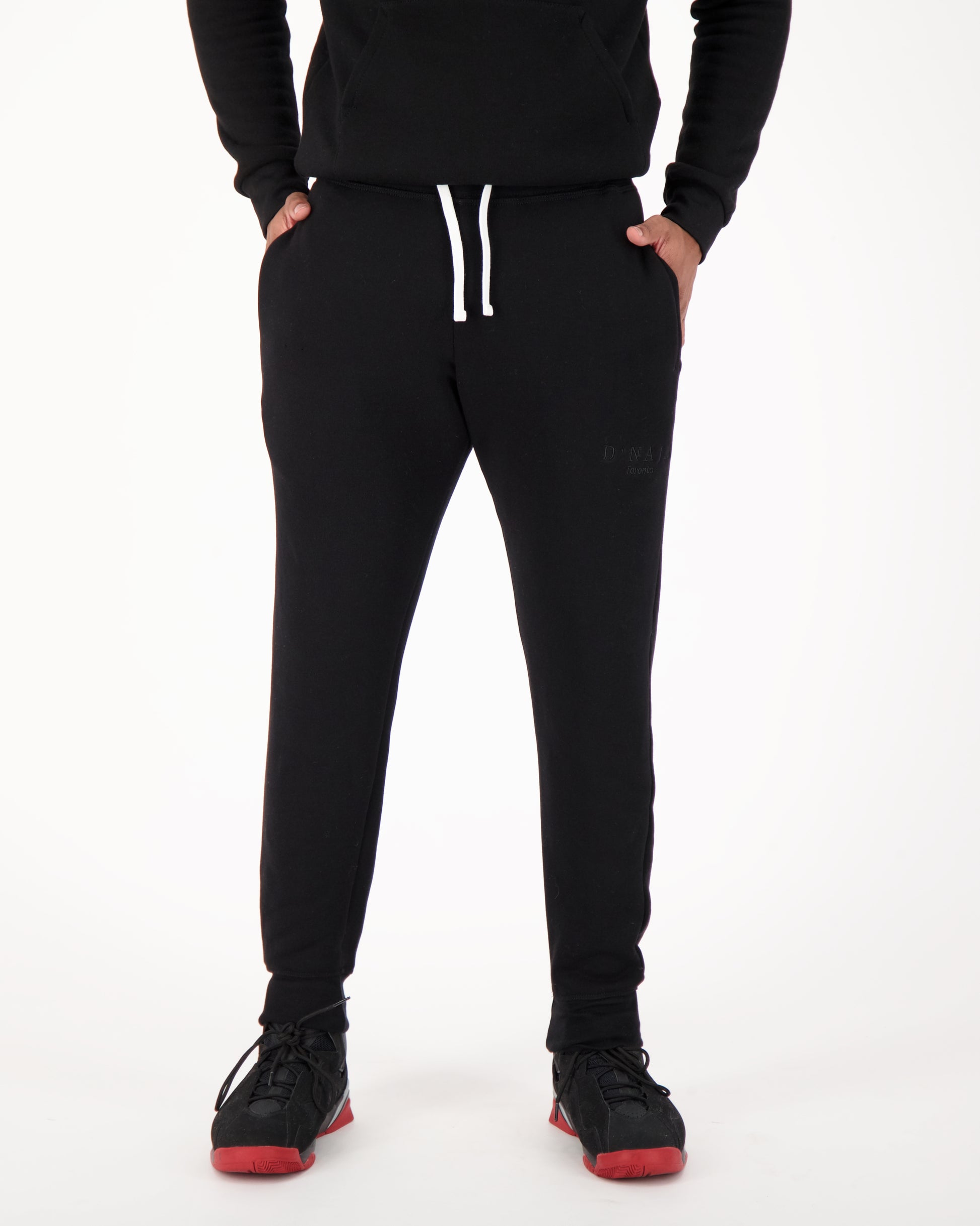 A man wearing black fleece sweatpants, radiating a relaxed and cozy vibe. The sweatpants are made of soft fleece fabric, providing warmth and comfort. The man's outfit exudes a casual yet stylish appeal. This is perfect for lounging, running errands, or enjoying leisure activities with ultimate comfort