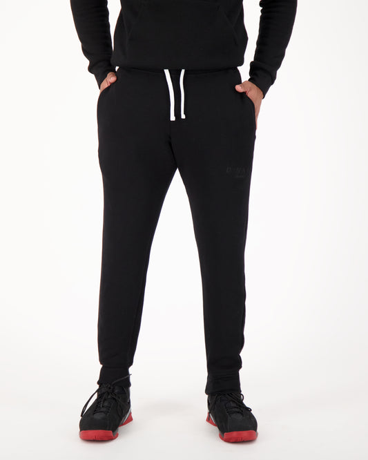 A man wearing black fleece sweatpants, radiating a relaxed and cozy vibe. The sweatpants are made of soft fleece fabric, providing warmth and comfort. The man's outfit exudes a casual yet stylish appeal. This is perfect for lounging, running errands, or enjoying leisure activities with ultimate comfort